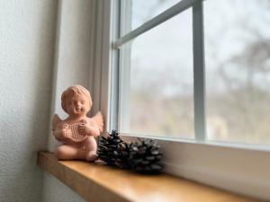 a figurine sitting on a window sill next to two pine cones at Yatsugatake Angel - Vacation STAY 75481v in Hokuto