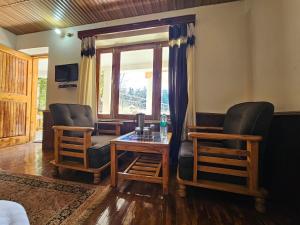 uma sala de estar com duas cadeiras e uma mesa em Purnima Guest House em Manali