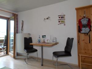 ホプフェラウにあるZimmer Alpseeのテーブルと椅子2脚が備わる客室です。