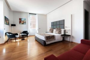 una camera con un letto e un divano rosso di Mascherino Suites a Roma