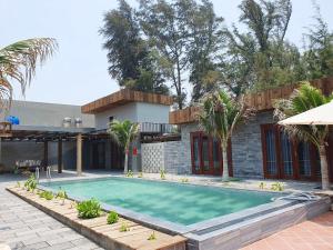 una piscina frente a una casa con palmeras en Chavi Beach - Coffee and Homestay en Bình Tú