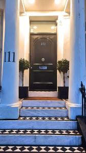 uma porta preta da frente de um edifício com escadas em It's The One One One in Notting Hill! -5- em Londres