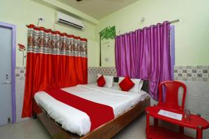 - une chambre avec un lit doté de rideaux rouges et d'une chaise rouge dans l'établissement Goroomgo Hotel Beach Heaven Puri Near Golden Sea Beach & Swargadwar, à Purî