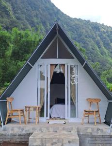 a tent with a bed and two chairs at Popitan Garden Campground & Glamping Bedugul in Bedugul