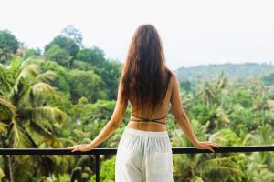 a woman standing on a balcony looking out at the forest at Marino Mirissa in Mirissa