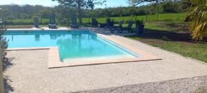 a swimming pool with blue water in a yard at La Petite Grange in Saint-Martin-Labouval