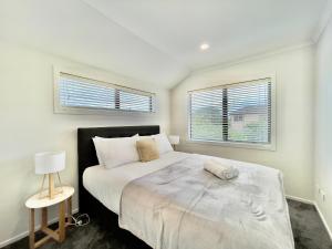 a bedroom with a large bed and two windows at Glendowie Brand-new comfortable 3 & 4-bedroom Houses in Auckland