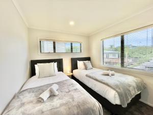 dwa łóżka w pokoju z dwoma oknami w obiekcie Glendowie Brand-new comfortable 3 & 4-bedroom Houses w Auckland