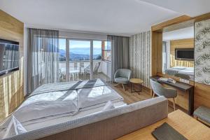 Schlafzimmer mit einem Bett, einem Schreibtisch und einem Balkon in der Unterkunft Hotel Hofbrunn in Riffian