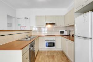een witte keuken met een wastafel en een koelkast bij Terralong Terrace Apartments in Kiama