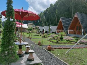 a garden with a table with a red umbrella at Popitan Garden Campground & Glamping Bedugul in Bedugul