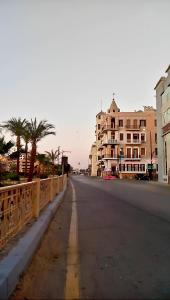 eine leere Straße in einer Stadt mit Gebäuden und Palmen in der Unterkunft Alam B&B Luxor in Luxor