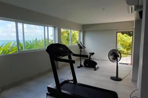 a gym with a treadmill and a fan and windows at Blue Bay Villa in Haad Yao