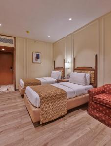 a hotel room with two beds and a couch at Hotel Residency Andheri in Mumbai