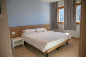 a bedroom with a white bed and two windows at Albergo La Romanella in Spinone Al Lago