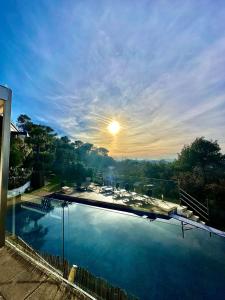 a large swimming pool with the sun in the sky at Aya House in Barcelona