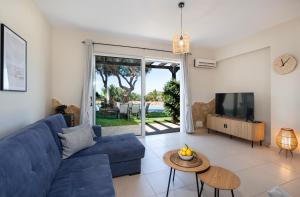 a living room with a blue couch and a tv at Gabriel apartment with a shared pool close to the beach in Chorafakia
