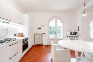 a white kitchen with a table and a white counter top at Villa Olivia in Forte dei Marmi