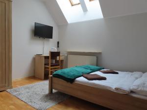 a bedroom with a bed and a desk with a television at Dobry Zakątek Dom Rekolekcyjny in Konstancin-Jeziorna