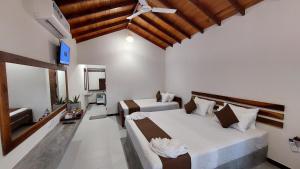 a bedroom with two beds and a ceiling fan at The Dream Inn Guesthouse Passikudah in Batticaloa