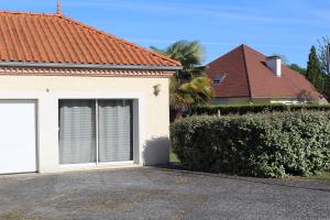 a house with a white garage door and a hedge at Studio 20m² au calme à Idron (5min de Pau) in Idron