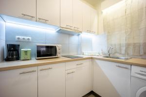 a white kitchen with a microwave and a sink at Acropolis Delux 1st FLR Aprt up 4 guests by LODGESPOT in Athens +24 photos