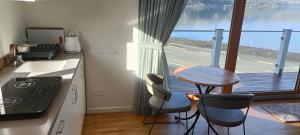 eine Küche mit einem Tisch und Stühlen sowie einen Balkon in der Unterkunft Luxurious waterfront accommodation in Dunedin
