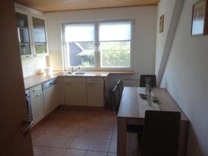 cocina con mesa de madera y 2 ventanas en Ferienwohnung auf dem Lande en Loxstedt