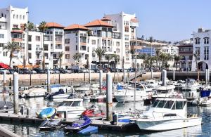 un groupe de bateaux amarrés dans un port de plaisance comportant des bâtiments dans l'établissement Moschea di Agadir, à Agadir