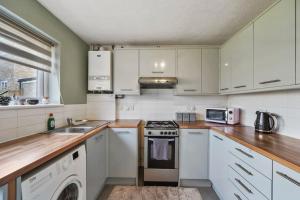 a kitchen with white cabinets and a stove top oven at Hidden Safari home in Canterbury with free parking in Kent
