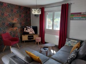 ein Wohnzimmer mit einem Sofa und einem roten Stuhl in der Unterkunft Entre Lacs Et Montagnes , Maison individuelle, lits préparés et ménage inclus in Barésia-sur-lʼAin