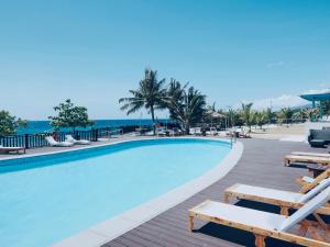 a swimming pool with chairs and the ocean in the background at W Golf Resort in Oslob