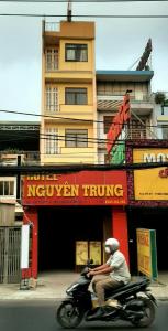 a man riding a motorcycle in front of a building at Khách Sạn Nguyên Trung in Ho Chi Minh City