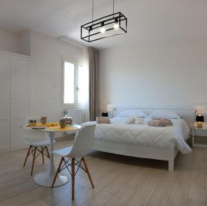 een witte slaapkamer met een bed en een tafel en stoelen bij mya luxury rooms and wellness in Melendugno