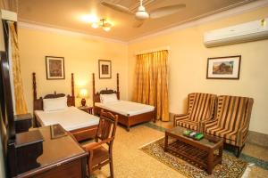 a living room with two beds and two chairs at Nilambag Palace Hotel in Bhavnagar