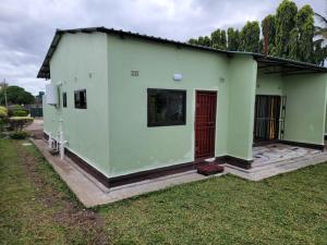 una casa verde con puerta roja en Mew3 Apartment, en Ndola