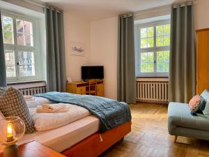 a bedroom with a bed and a couch and windows at Kavaliershaus neben Schloss Rauenstein 