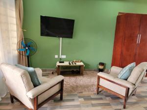 a living room with two chairs and a flat screen tv at Mew3 Apartment in Ndola