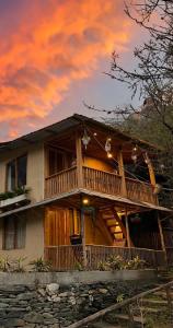 a large wooden house with a large deck at Aloha Riverside in Kasol