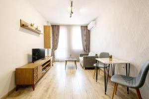 ein Wohnzimmer mit einem TV, einem Tisch und Stühlen in der Unterkunft Central Point Premium + in Ruse