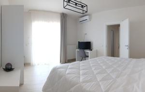 a white bedroom with a bed and a television at mya luxury rooms and wellness in Melendugno
