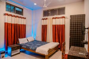 Schlafzimmer mit einem Bett mit roten und blauen Vorhängen in der Unterkunft bornil guest house in Guwahati