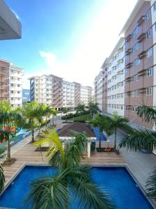 a resort with a pool and palm trees and buildings at Apartment Condotel at Hope Residences Trece Martires Cavite in Trece Martires