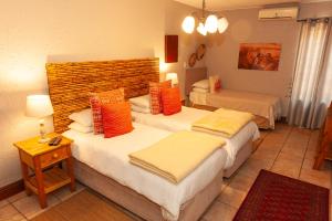 a hotel room with two beds with orange pillows at Safari Club Guest Lodge OR Tambo International Airport in Kempton Park