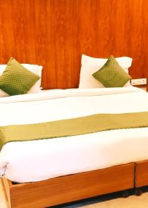 Cama con sábanas blancas y almohadas verdes en Hotel Aroma Residency Premium 47 Corporate,Family,Friendly,Couple Friendly Near - Unitech Cyber Park & IKEA en Gurgaon