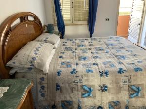 1 dormitorio con 1 cama con edredón azul y blanco en Come a Casa!, en Oristano
