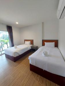 two beds in a hotel room with a window at Sisina Resort and Spa in Prachuap Khiri Khan