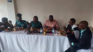 a group of people sitting around a table eating food at KWERI GUEST HOUSE in Mbarara