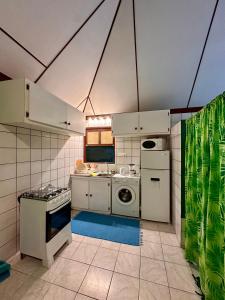 een keuken met witte kasten en een wasmachine en droger bij « Le Green House » by Meri lodge Huahine in Fare