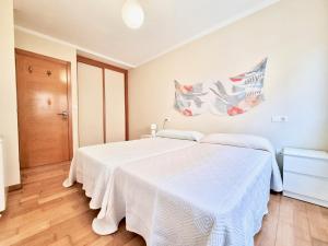 a bedroom with a white bed and a wooden floor at Apartamento en la playa! in Sanxenxo